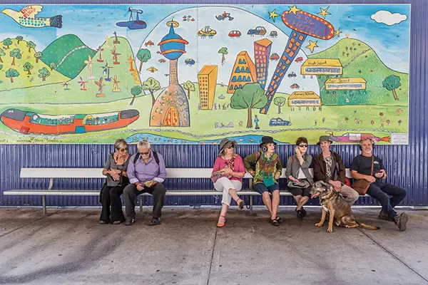 A colour photo of a group of people beneath a large mural