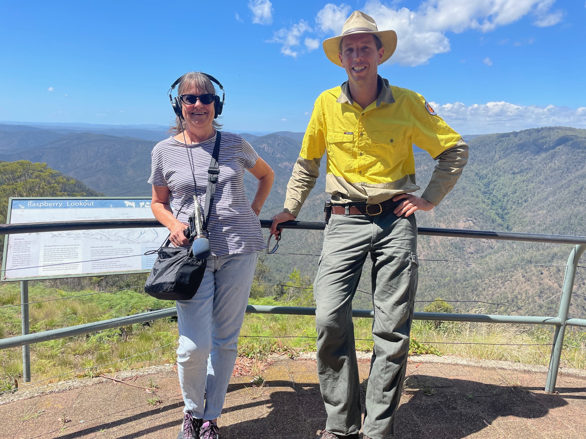 Two people standing on a viewing platform above a magnificent natural mountainous landscape