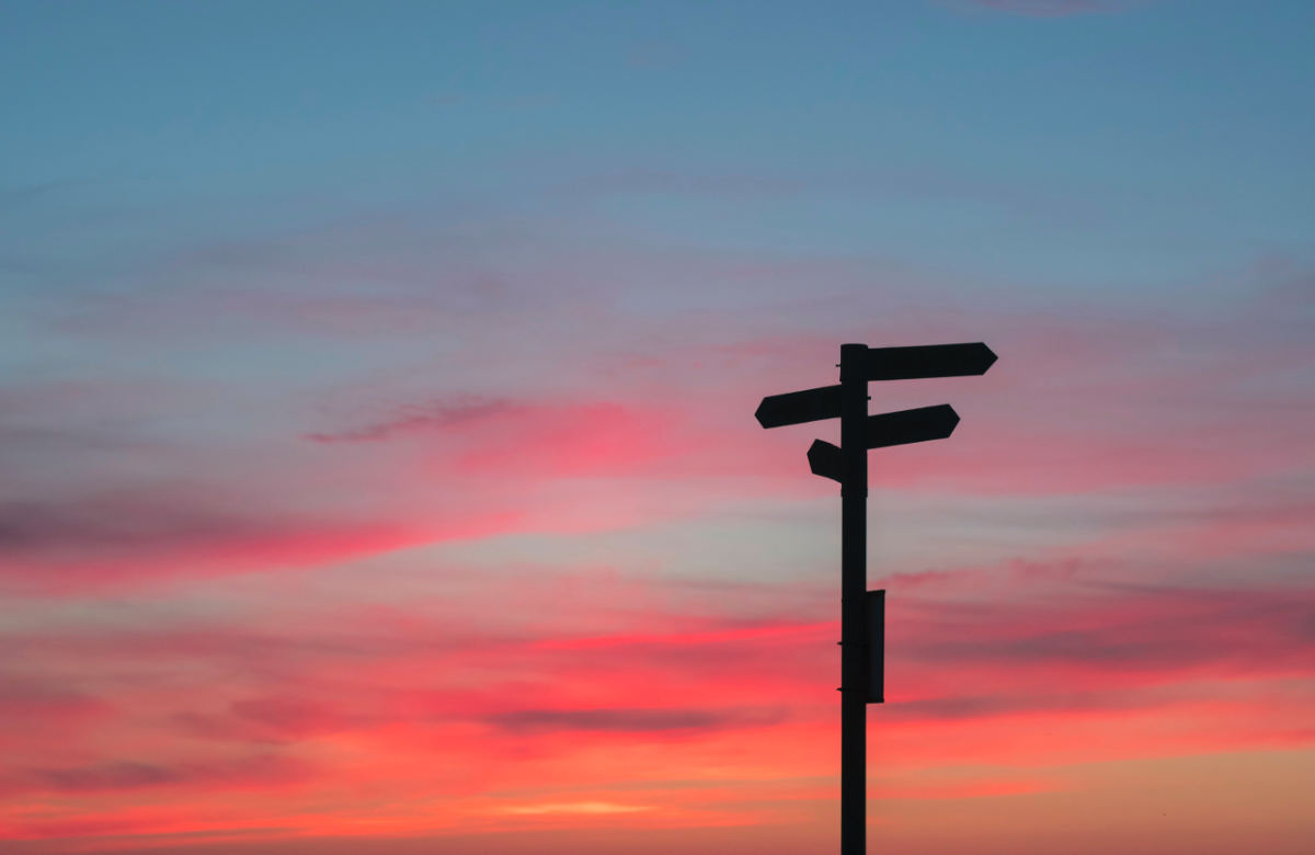 photo of a silouette of a signpost against red and blue sunset sky
