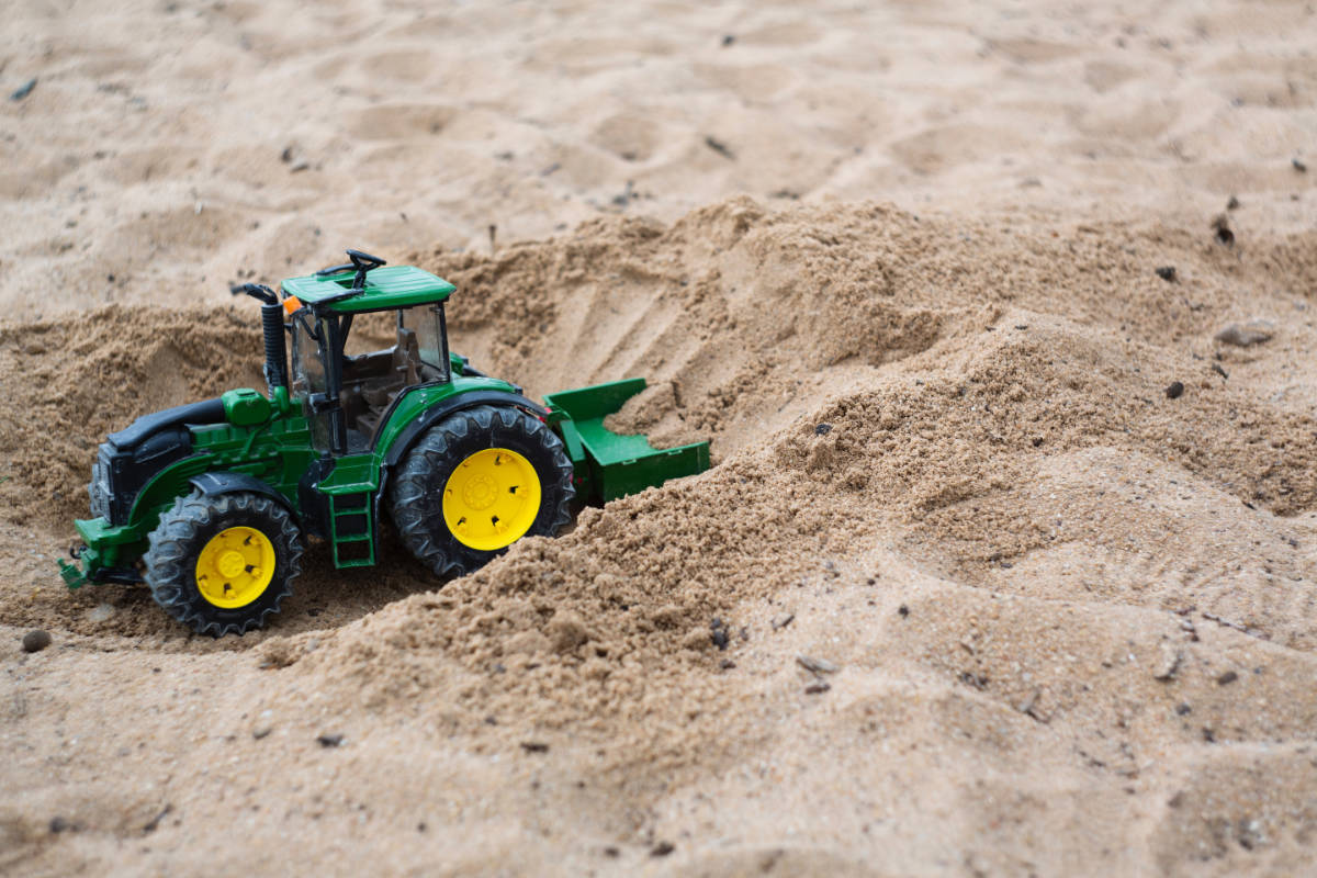 Green toy tractor in sand