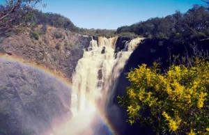 Gushing big waterfall rainbow glittering in front