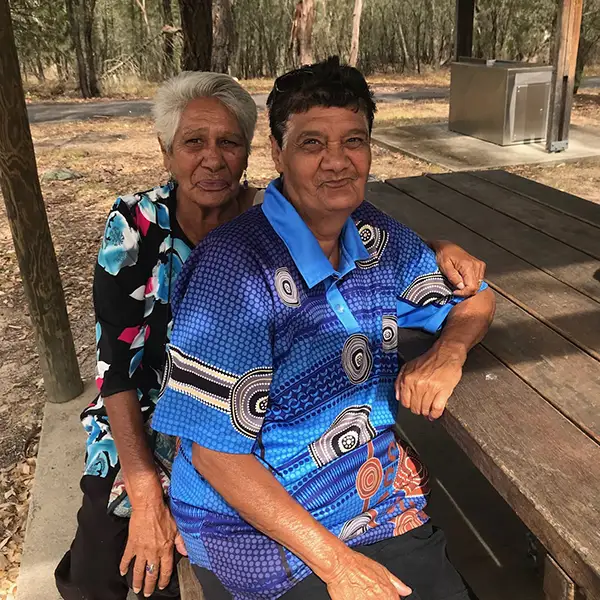 Two women in colourful shirts sitting at a park bench