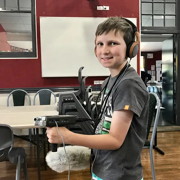 A boy with recording gear standing inside