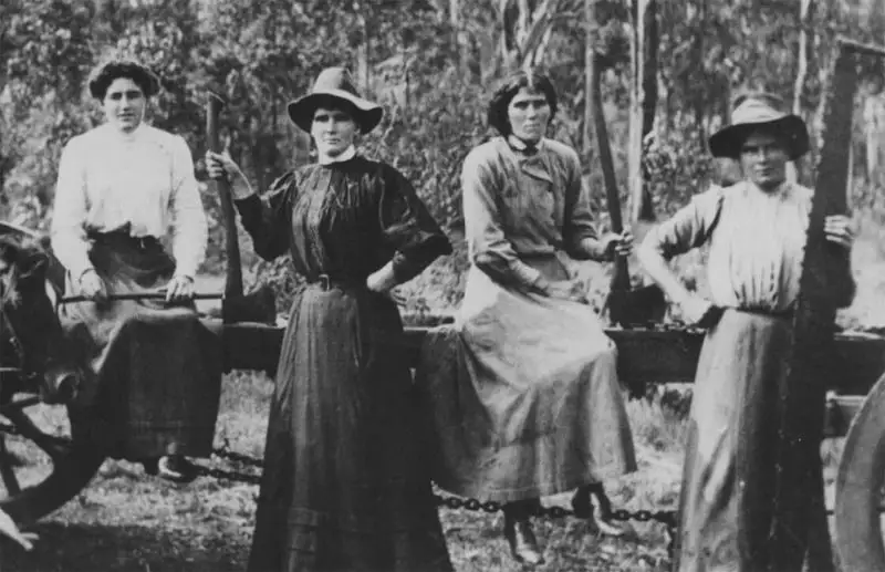 Old black and white photo of four serious looking women in front of a wagon