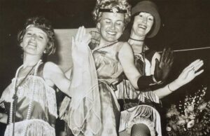 Black and white photograph of three women in roaring twenties outfits, smiling and having a lovely time