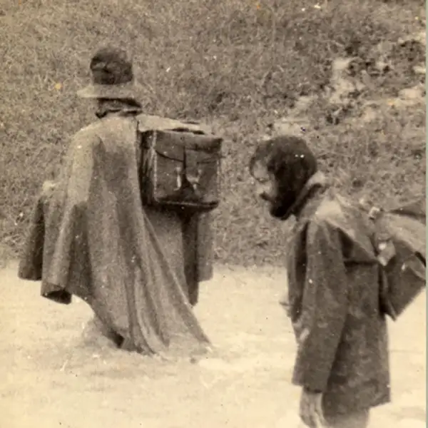 two men in raincoats with instruments wading through a flowing stream