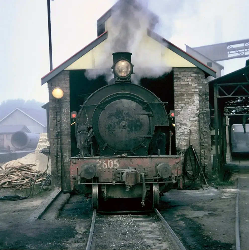 Steam Train coming out of an industrial shed