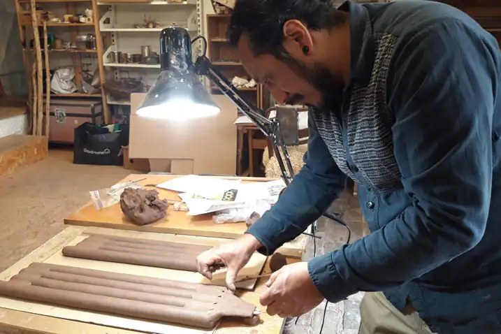 A man in a workshop is reconstructing an ancient claypipe