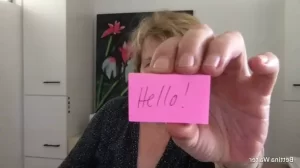 person holding up a postit note saying 'Hello'