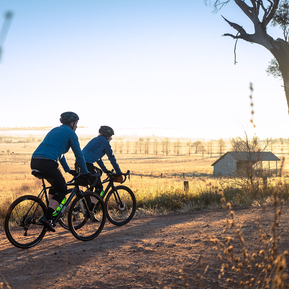 two bicycle riders on a gravel road in the golden light of the glorious Highlands rural landscape