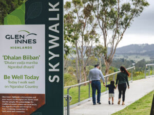 In the foreground is Skywalk signage. In the background a family is walking on a path towards a lookout.