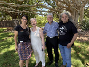 A group of four people in the dappled shade of a tree.