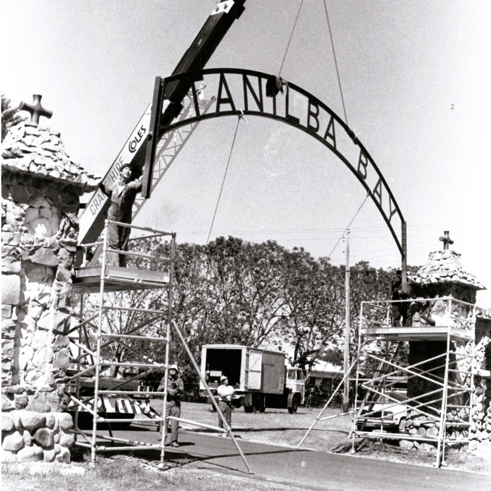 A crane hoisting the sign Tanilba Bay onto the stone gates