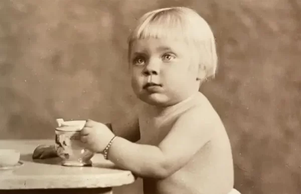 Vintage sepia coloured studio photo of a very blond little girl with a porcellane cup.