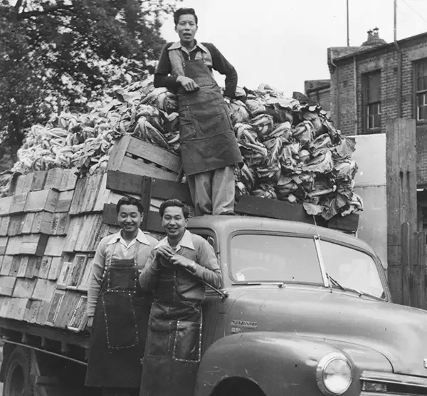 Three men standing on a truck laden with vegetables