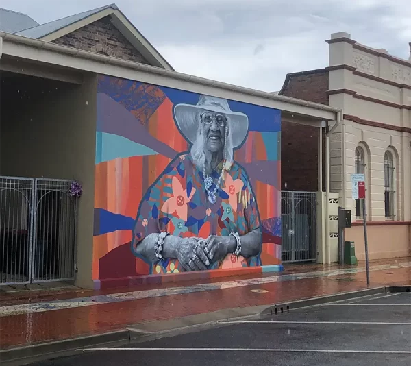 photo of a big mural of Elizabeth Connors in sun hat and glasses